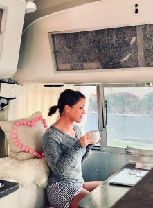 Jaci drinking coffee at the table in her Airstream