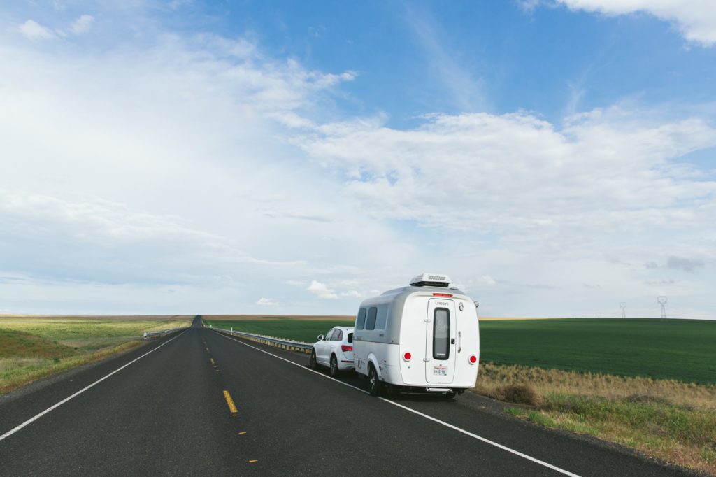 airstream nest being towed by audi on open highway with blue skies