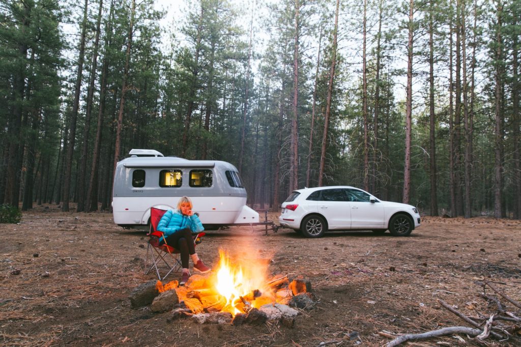 airstream nest at campsite with campfire and audi with laura austin in woods