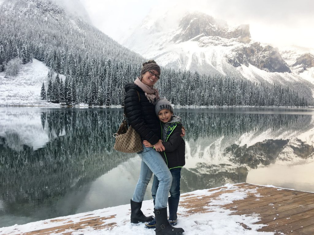 Airstream Ambassador Diane Tripels standing by lake and snow covered trees