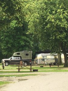 Airstream and Travel Trailer with a truck and trees