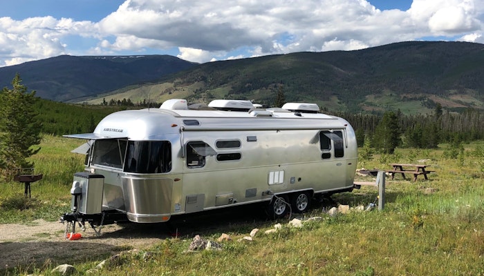 Airstream Travel Trailer RV Camper Trailer in mountain scene with grass