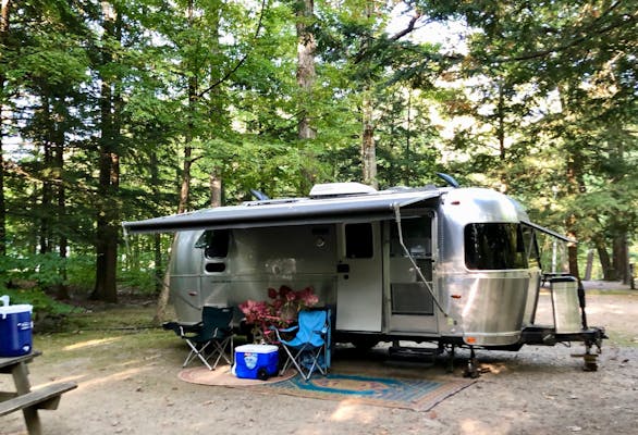 Airstream Travel Trailer RV Camper Trailer set up at campsite in woods