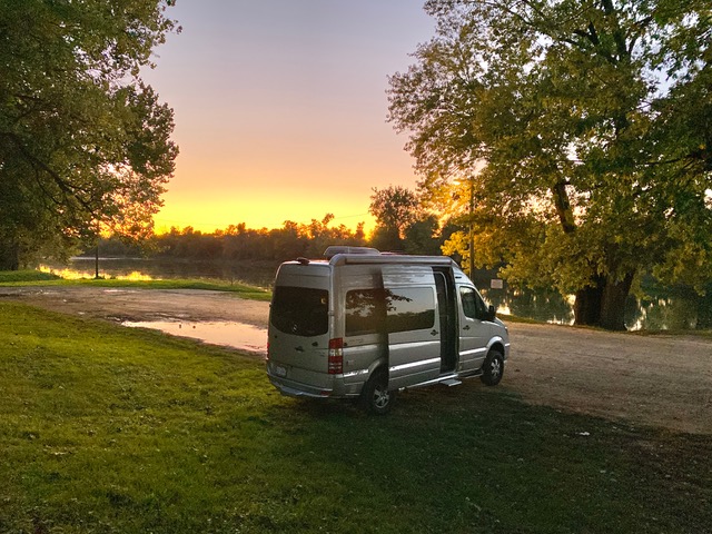 Airstream Interstate Nineteen Sunset by water and trees