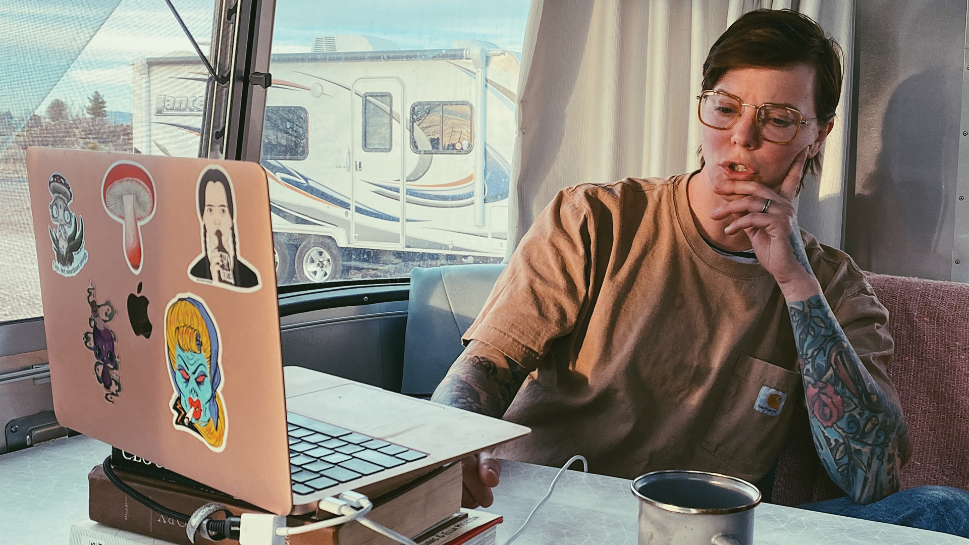 Regan sitting on her laptop at the table in her Airstream