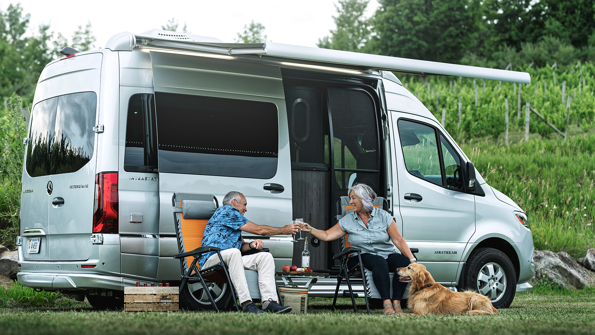 A couple sitting outside touring coach with dog