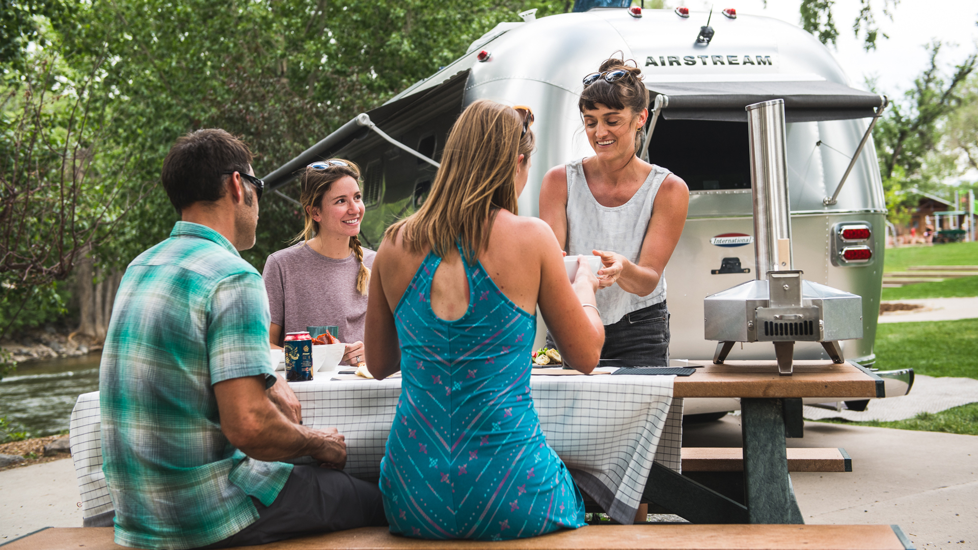 people-hanging-out-at-a-picnic-table-by-their-Airstream