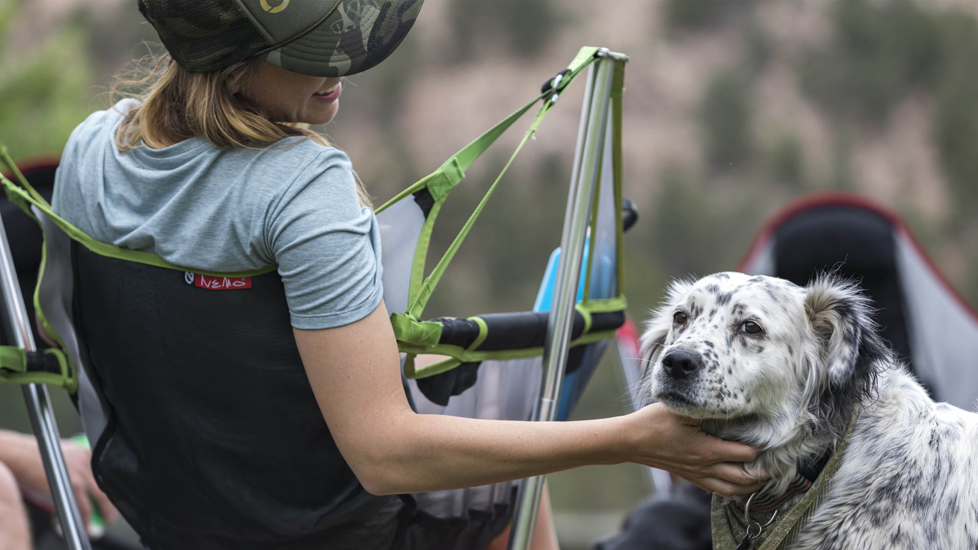 A woman sitting in a chair petting her dog