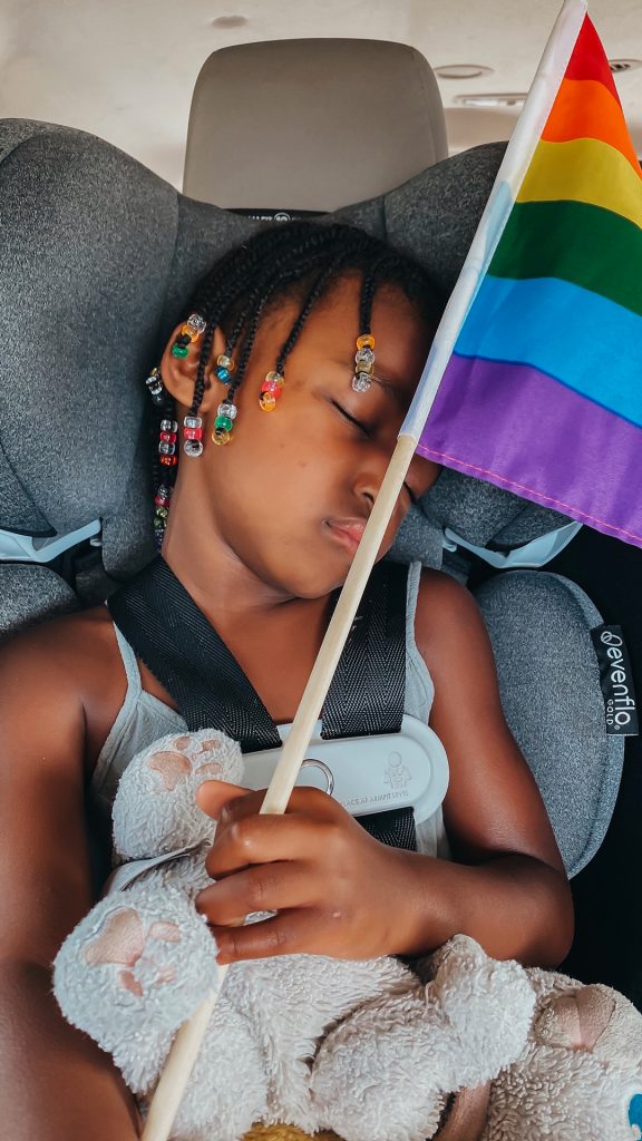 Charlotte sleeping in her car seat with a LGBTQ+ flag