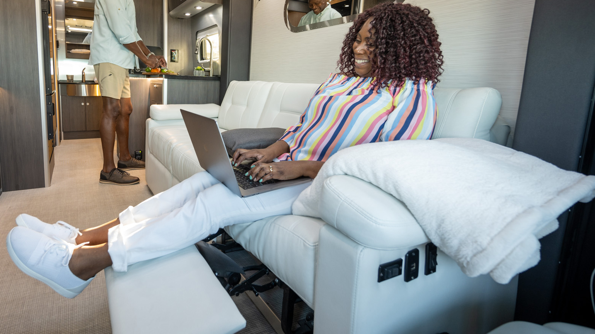 Female Airstreamer sitting on the sofa in her Touring Coach on her computer