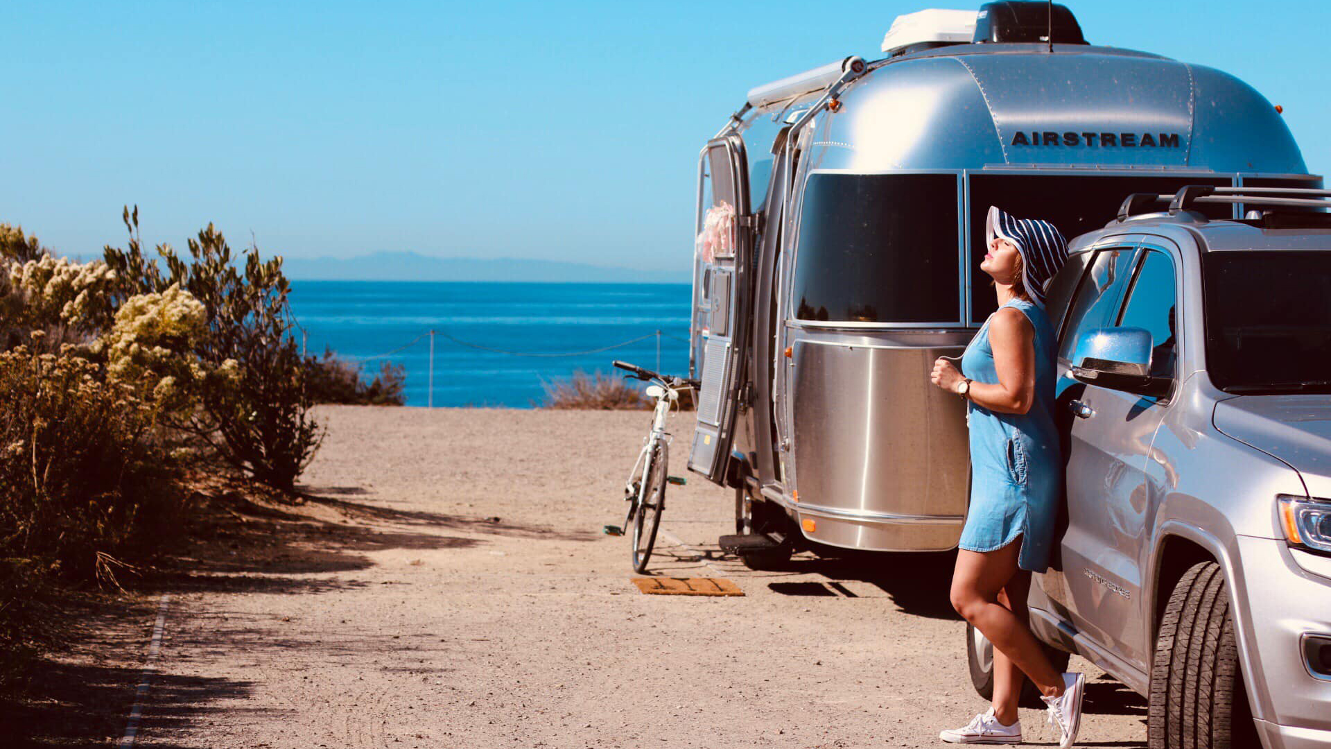 Jaci standing with Airstream on the beach