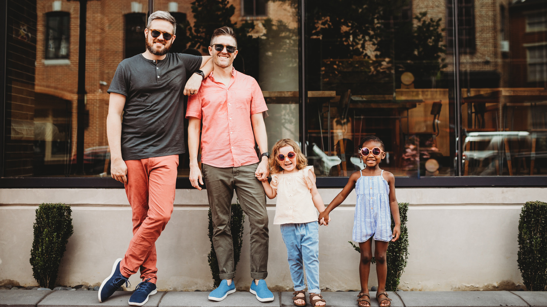 Jonathan and Thomas with their daughters outside with sunglasses on