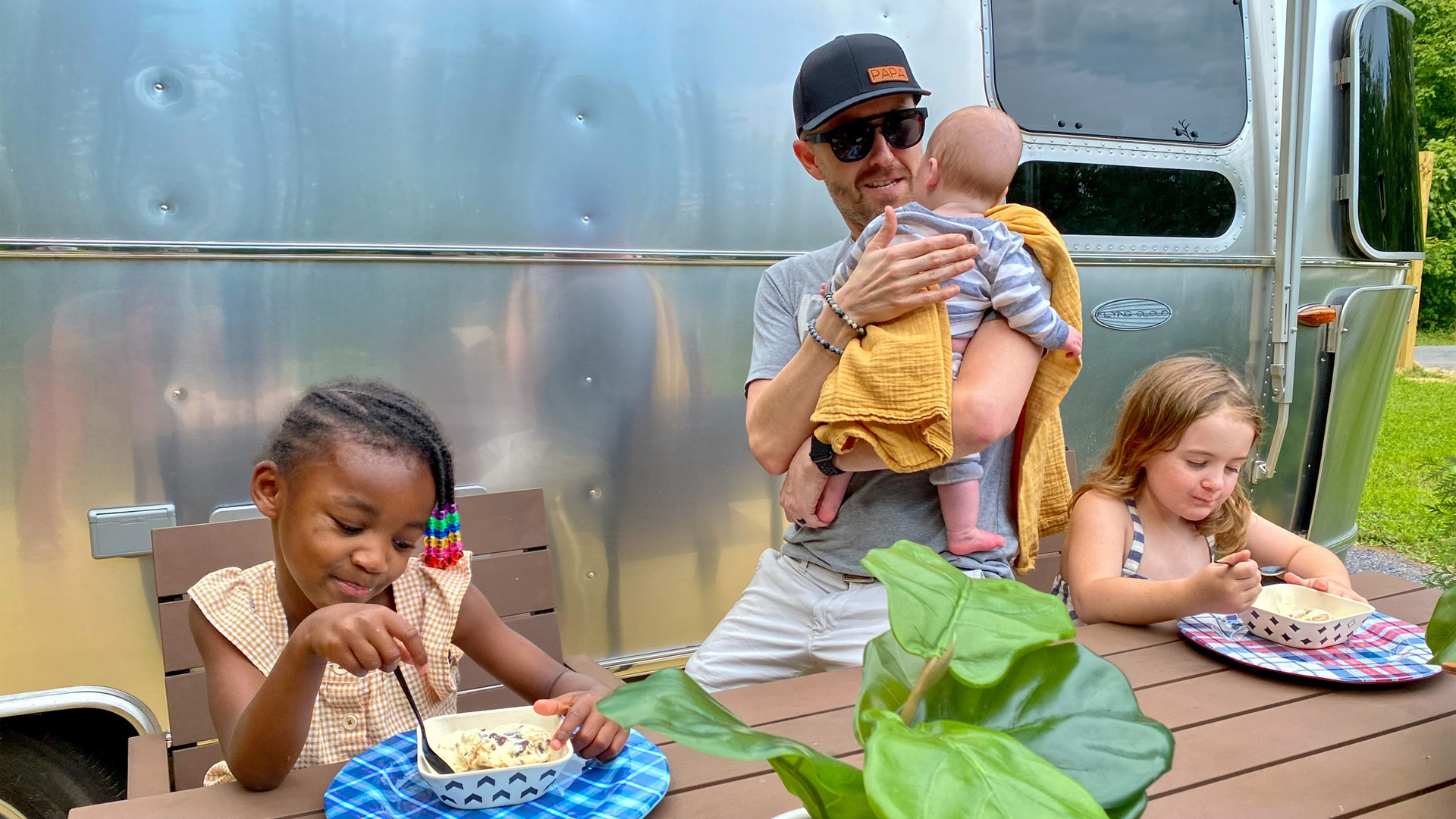 Jonathan and Thomas's Kids sitting at a table outside by their Airstream Travel Trailer