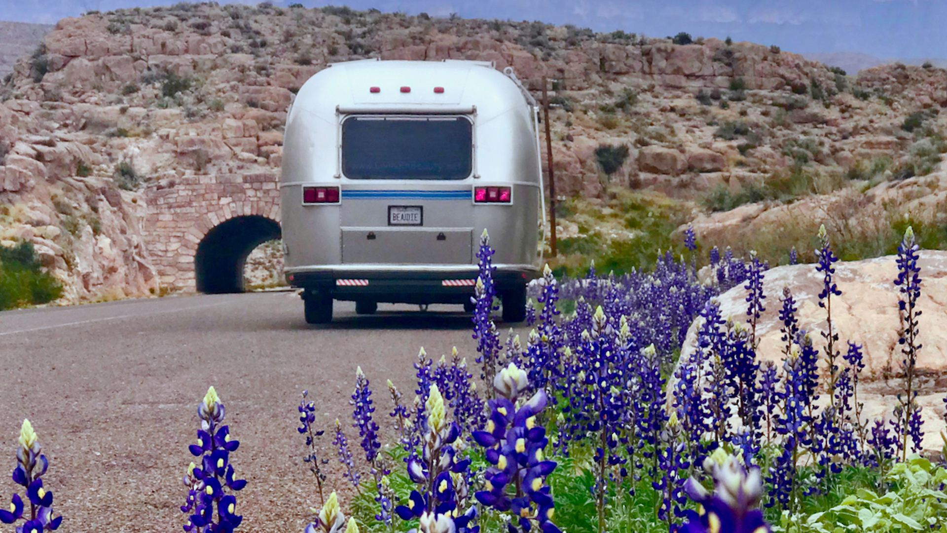 Airstream driving down the road in the desert