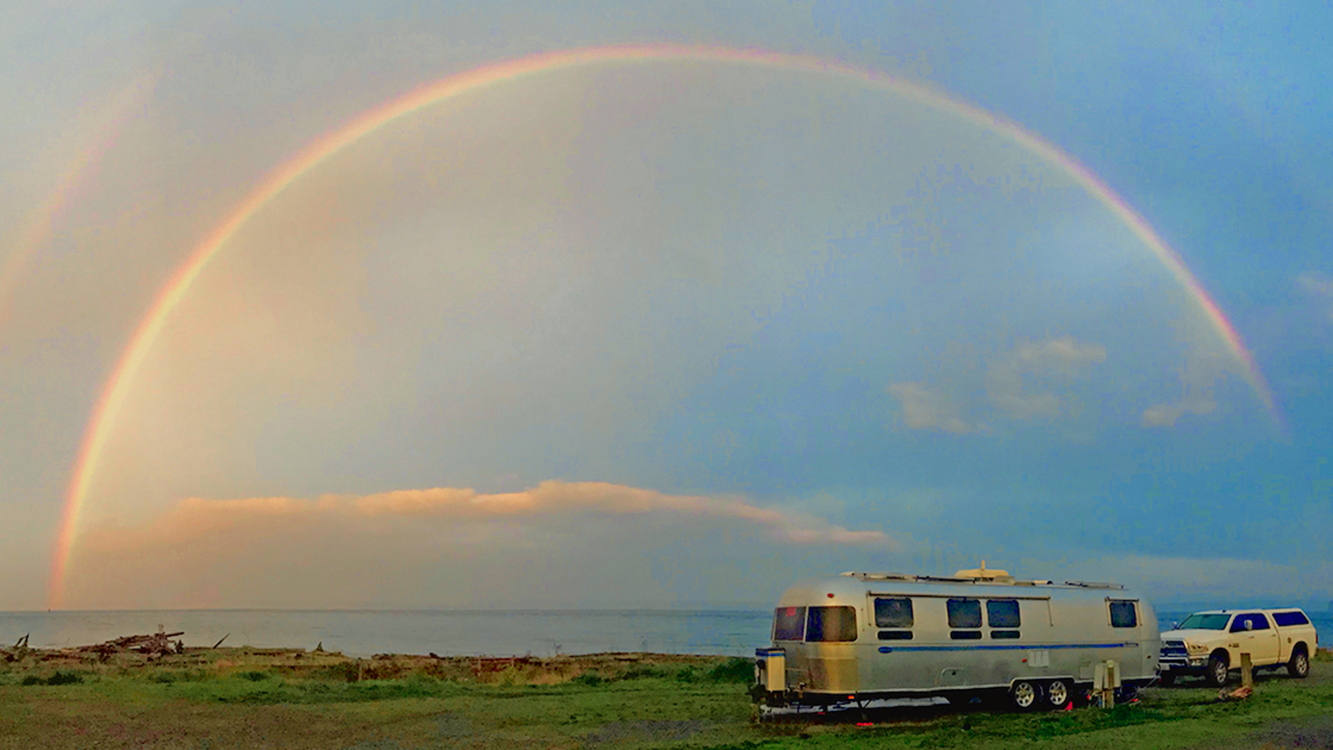 Airstream parked with a rainbow in the sky