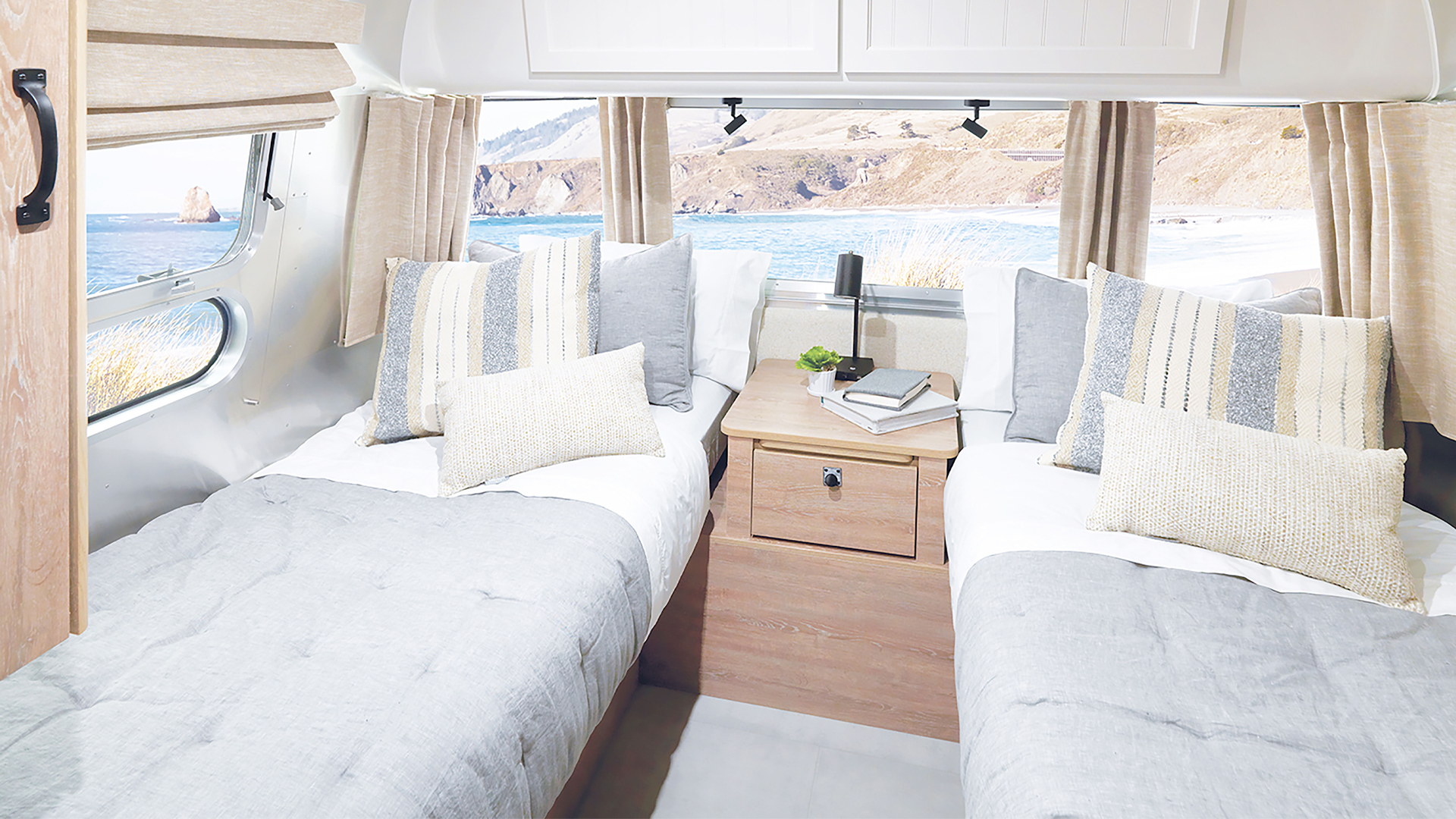 Airstream Pottery Barn Special Edition Travel Trailer bedroom with twin beds and side table looking out at the ocean