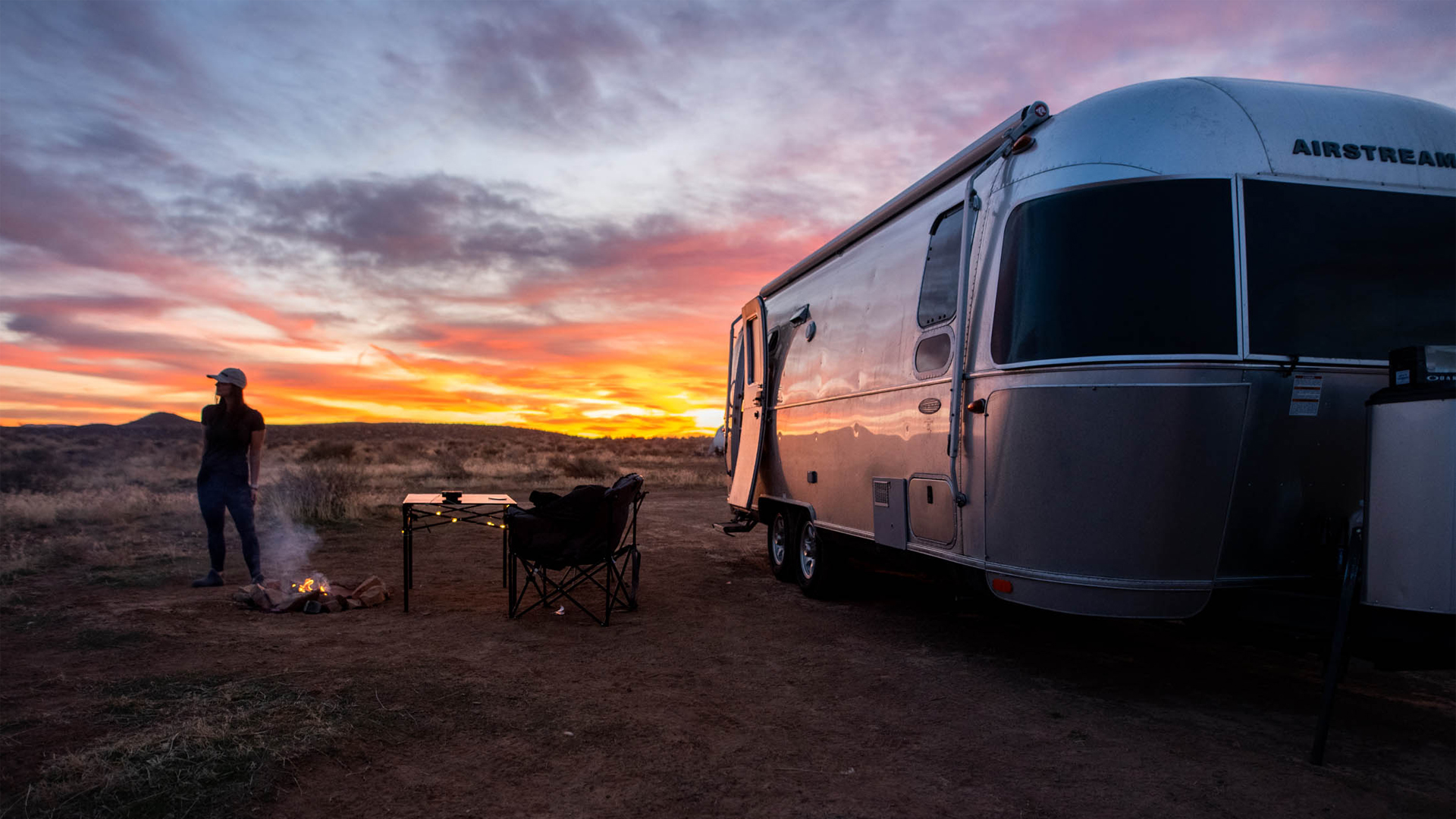 Woman watching the sun set outside of her Airstream Travel Trailer