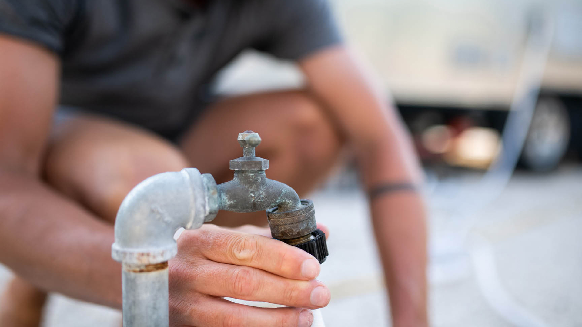 A guy attaching his water hose for his Airstream Travel Trailer