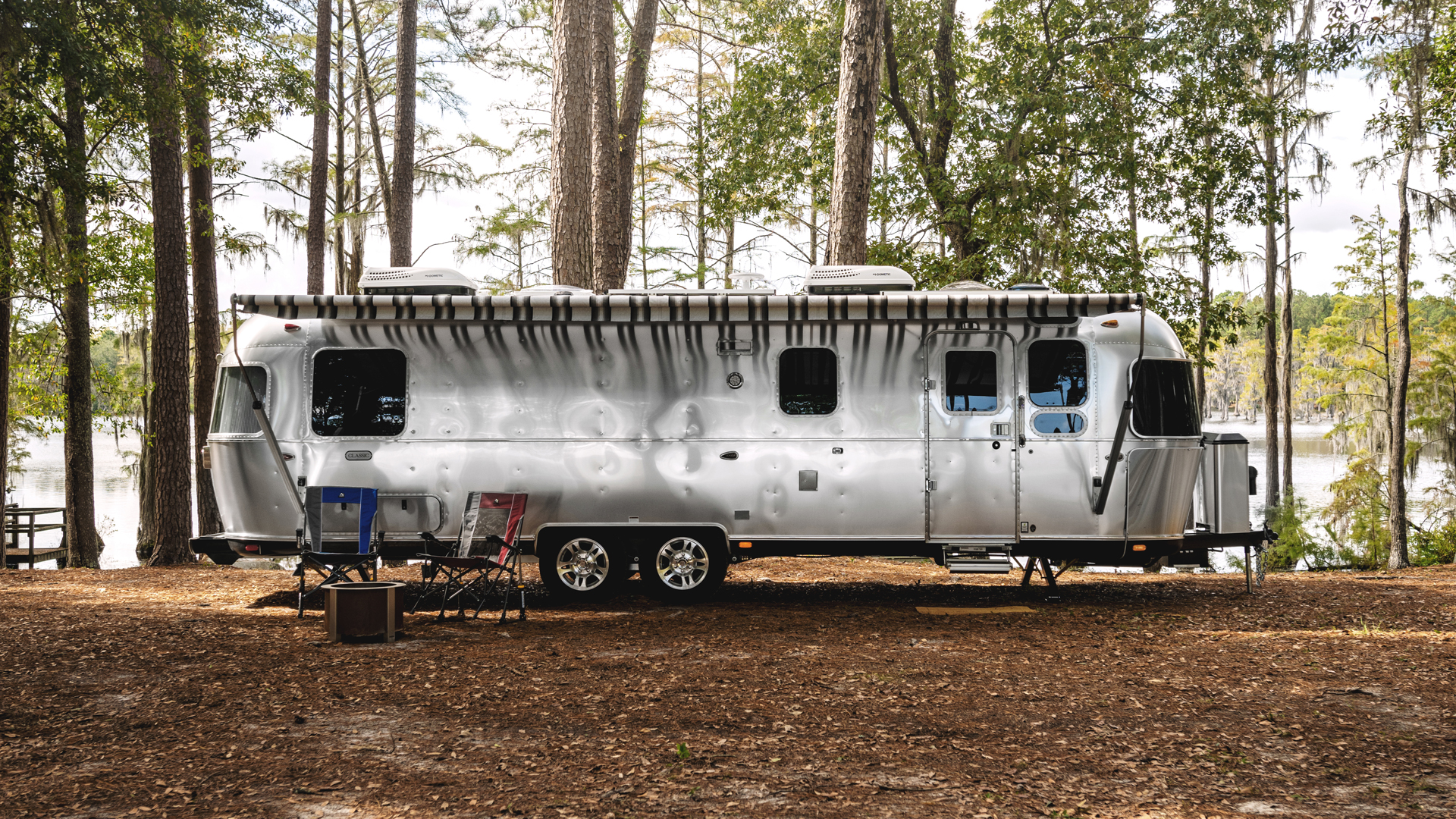 Airstream Classic Travel Trailer with the awning out in a woods