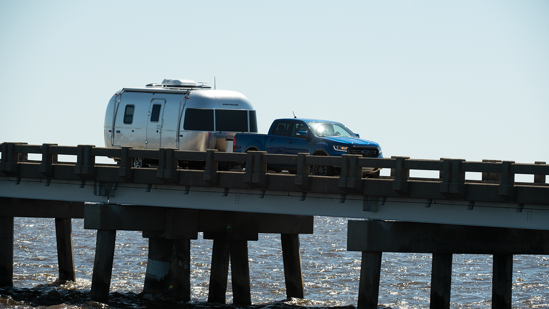 A truck pulling an Airstream Travel Trailer across a bridge