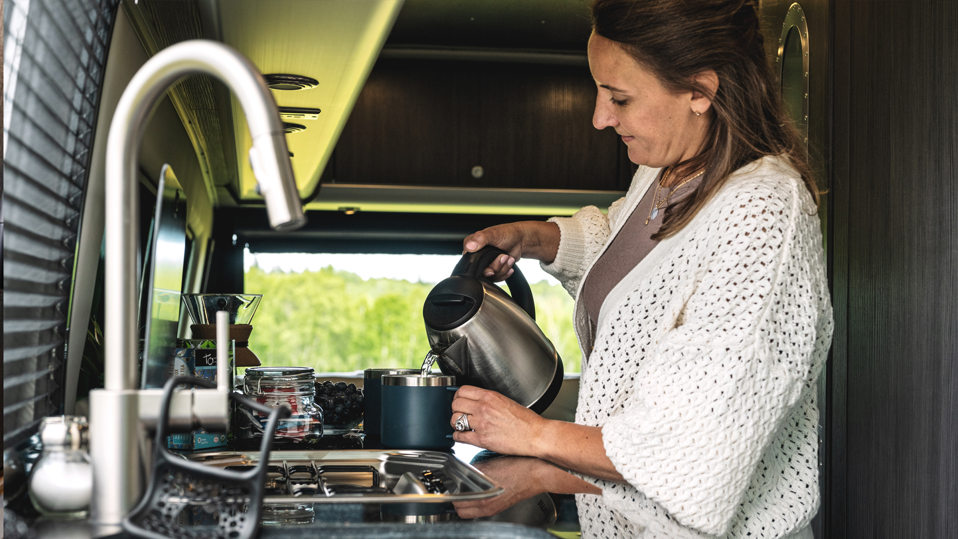 A woman pouring coffee in the kitchen of her Airstream Interstate 24 Touring Coach