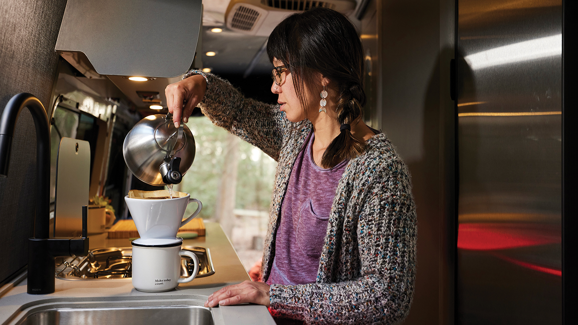 A woman making coffee in her french press in her Airstream Interstate 24X