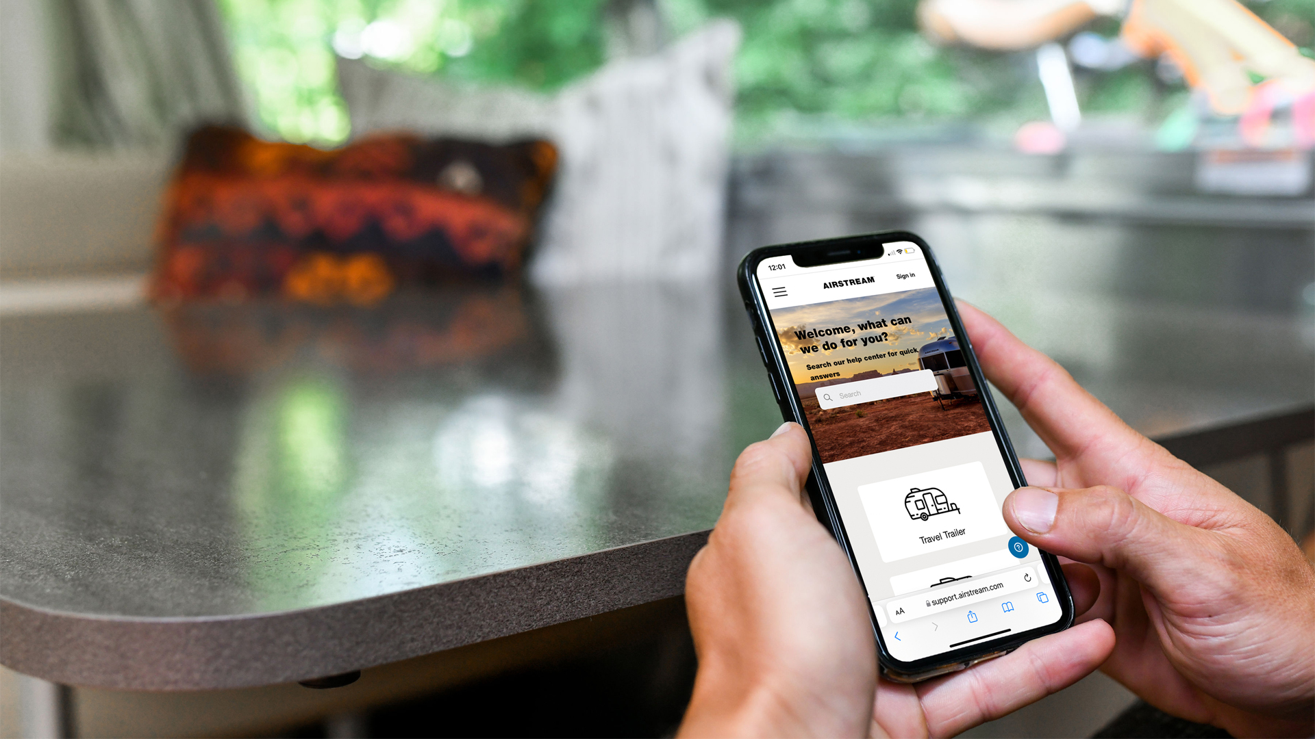 A person sitting in their Airstream Travel Trailer pulling up Airstream Support in their iPhone.