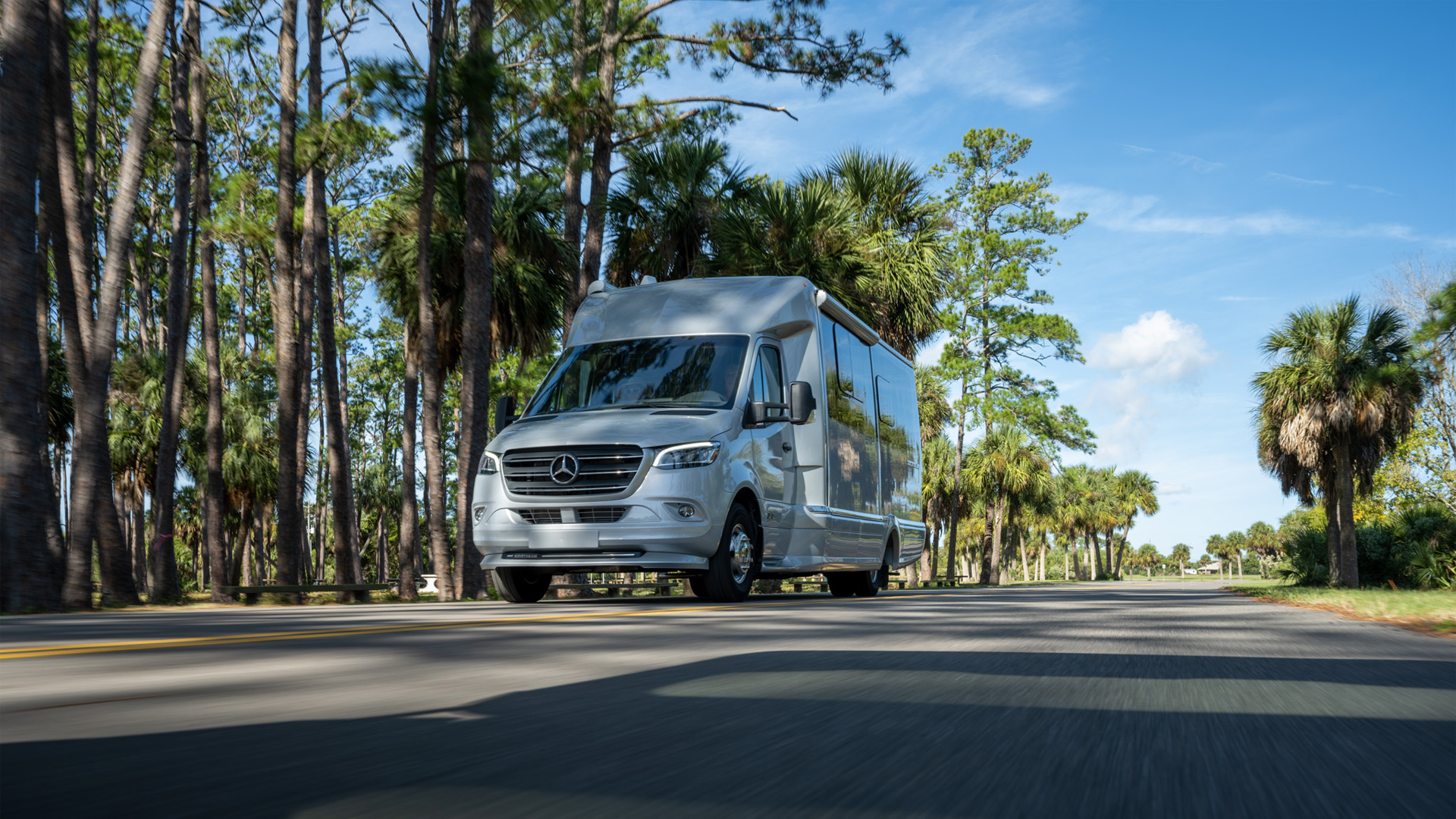 Airatream Atlas Class B Motorhome driving down the road by palm trees