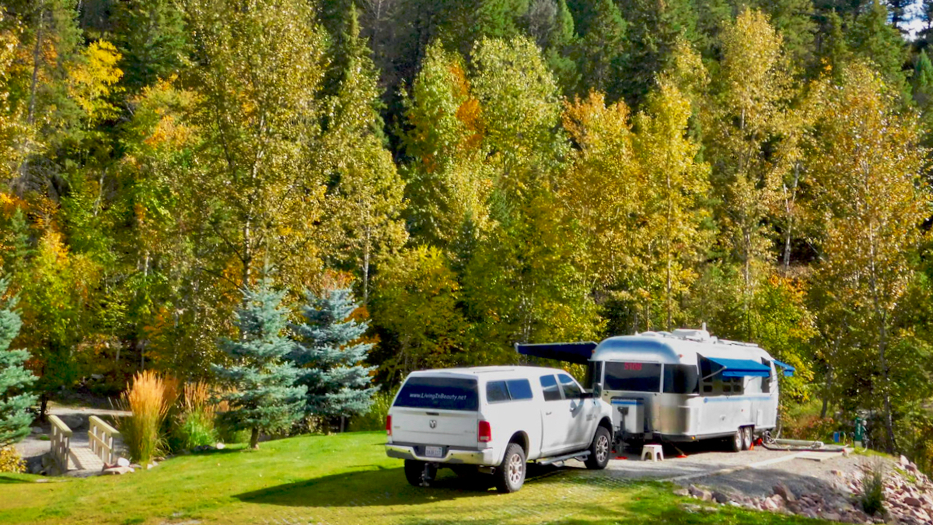 Airstream travel trailer parked in the woods during fall.