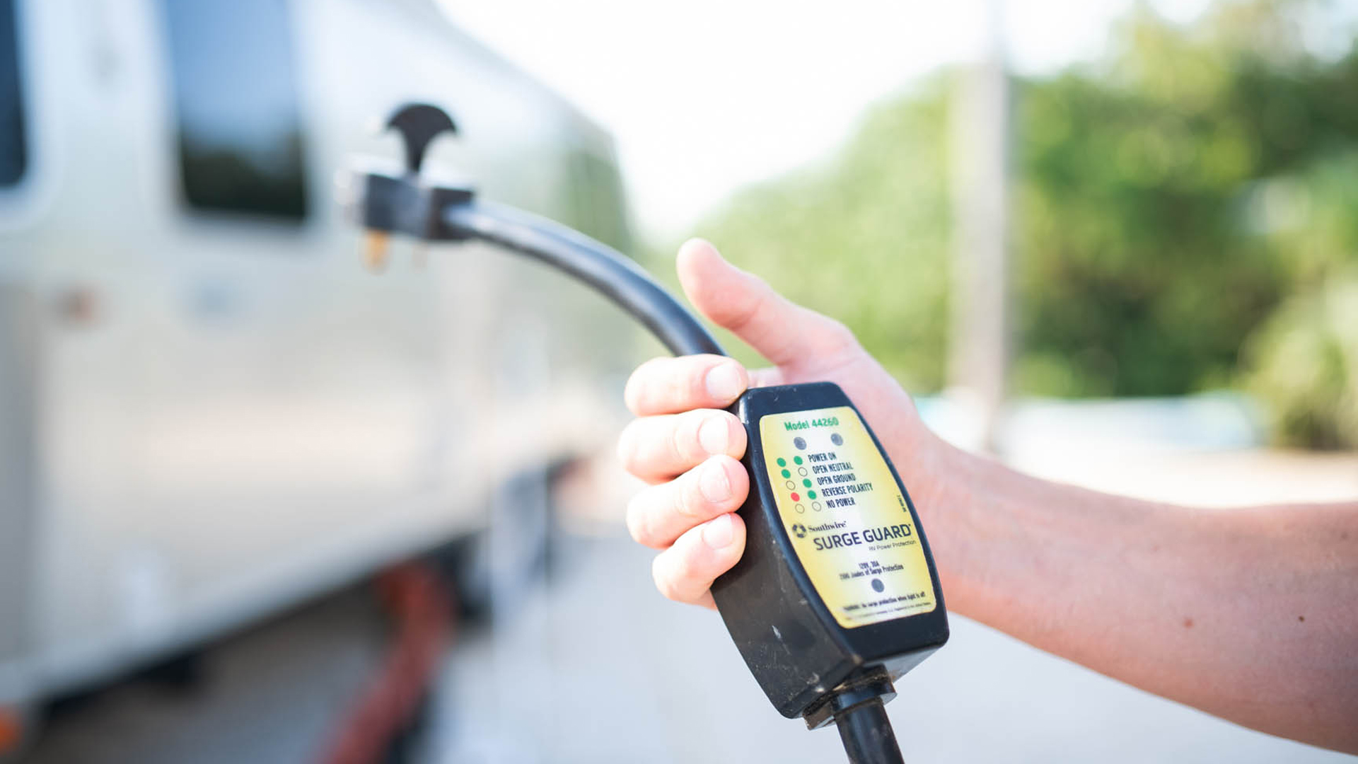 A person using a surge guard on their Airstream travel trailer.