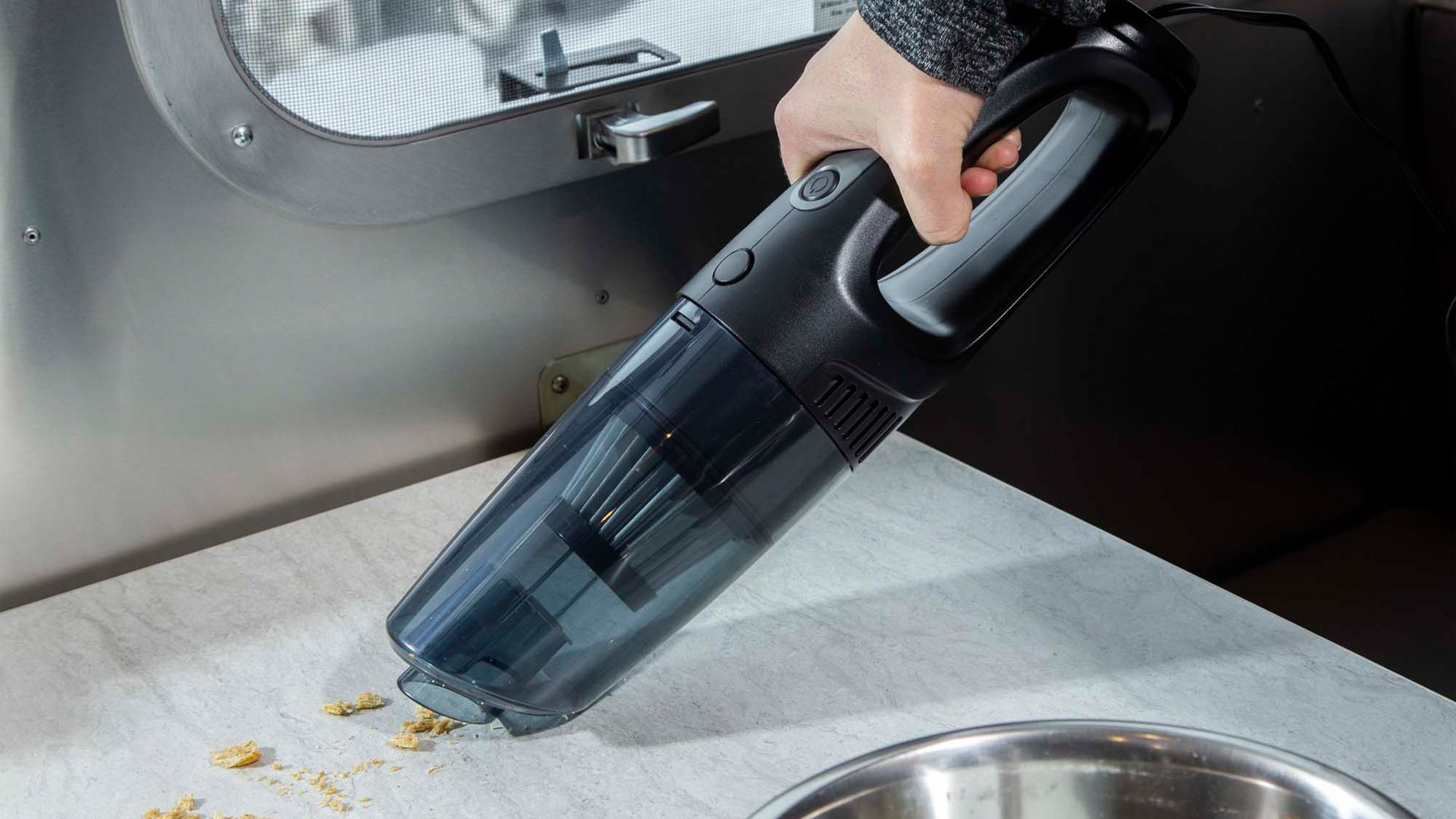 A person using a hand held vacuum in an Airstream travel trailer.