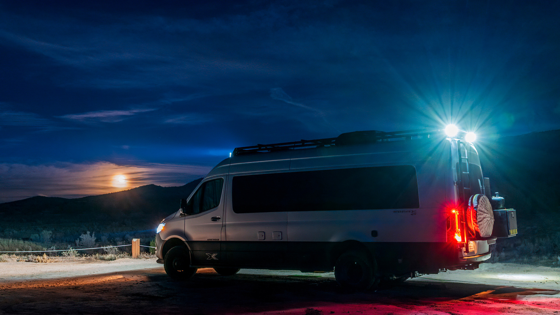 Airstream Interstate 24X sitting off the road in the dark at night with its lights on