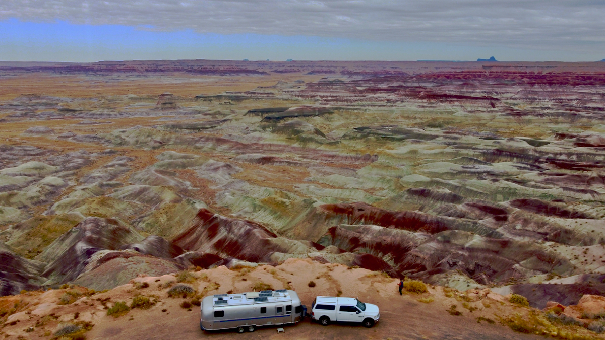 An Airstream Classic Travel Trailer being towed through the mountains of the desert.