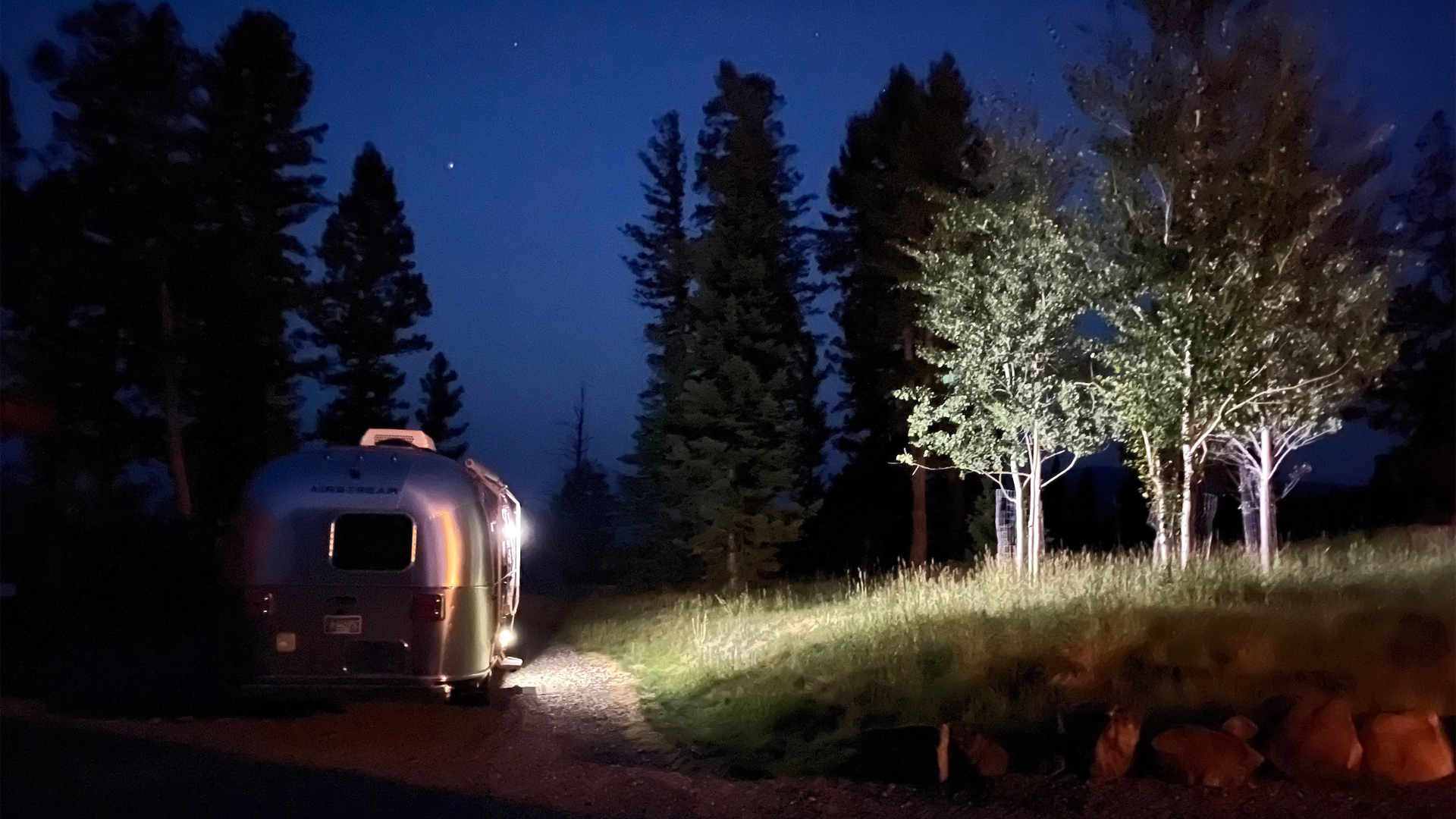 An Airstream travel trailer parked at an RV park at night.