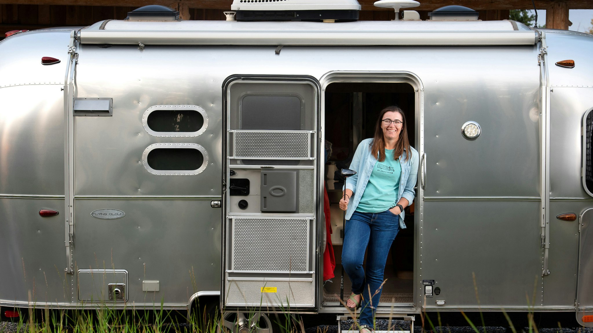 Dorsey Addicks inside the door of her Airstream Flying Cloud travel trailer holding a golf club.