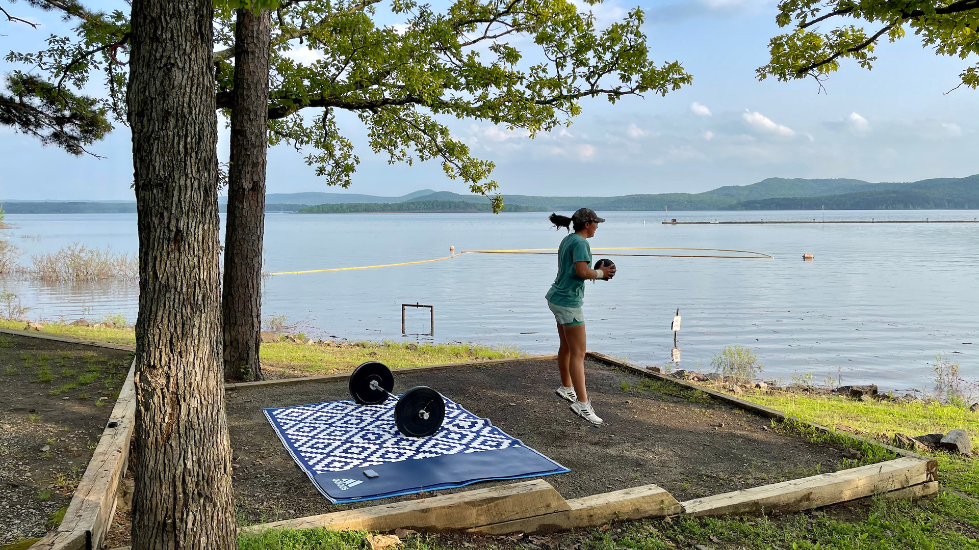 Dorsey Addicks working out outside of her Airstream travel trailer that is parked next to a lake.