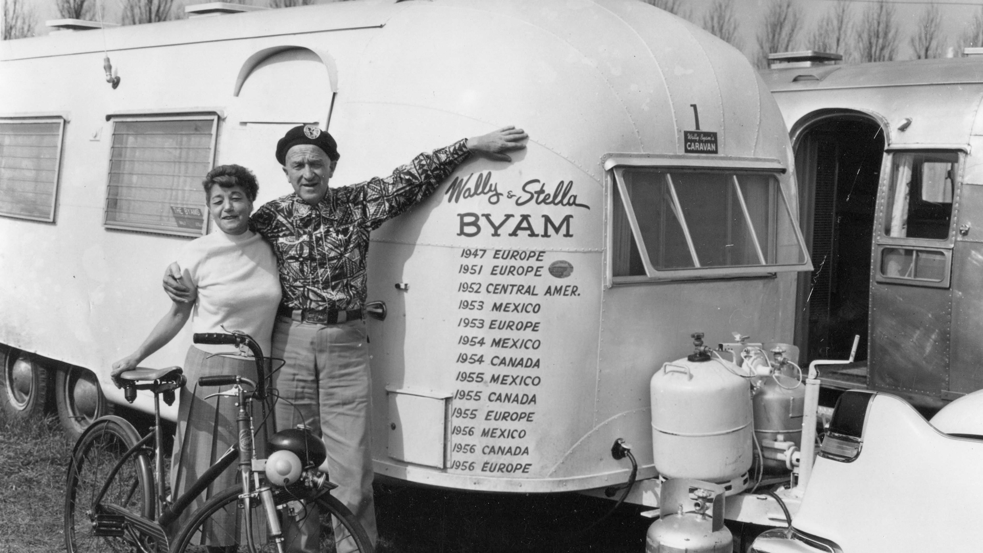 Airstream Founder, Wally Byam and his wife Stella, stand next to the White Trailer that was used to travel through Europe