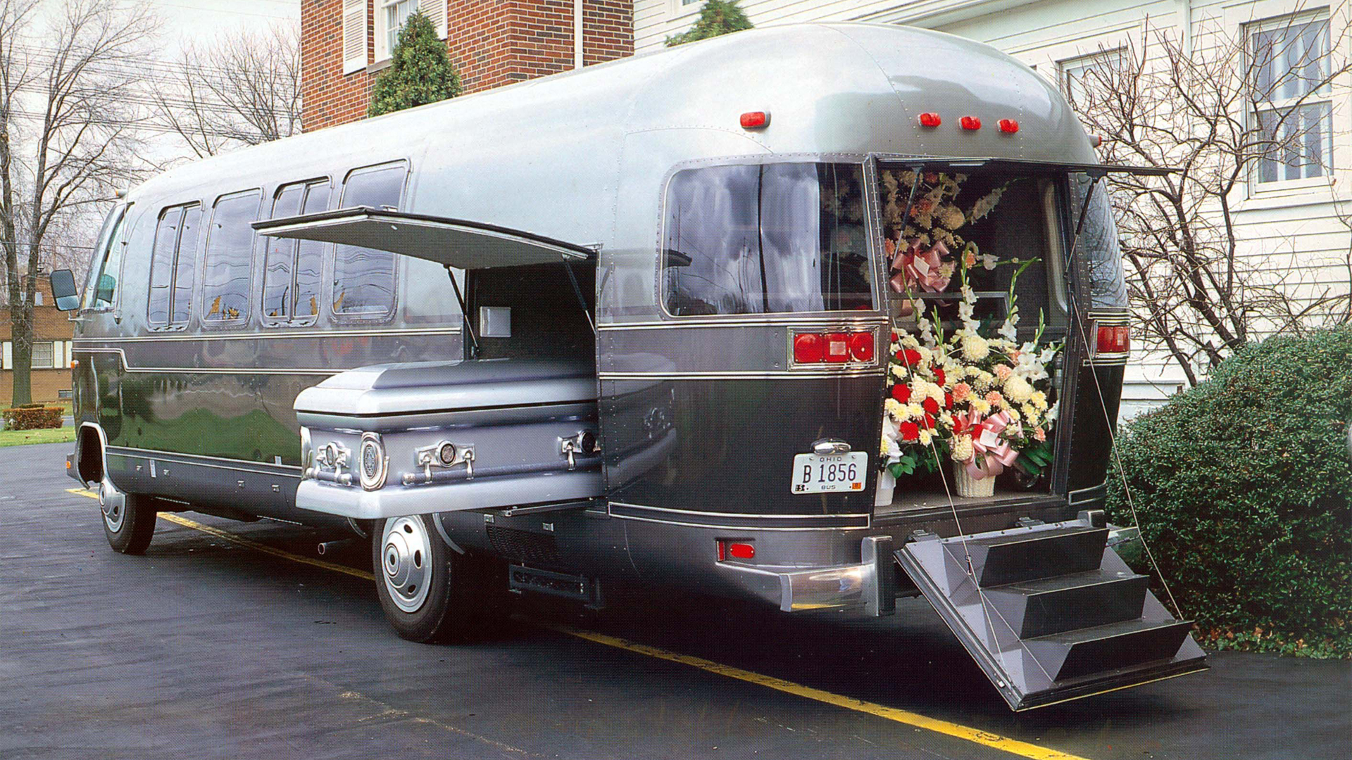 Vintage Airstream Funeral Coach sitting at a funeral home with flowers in the back and a coffin in the side of the Airstream.