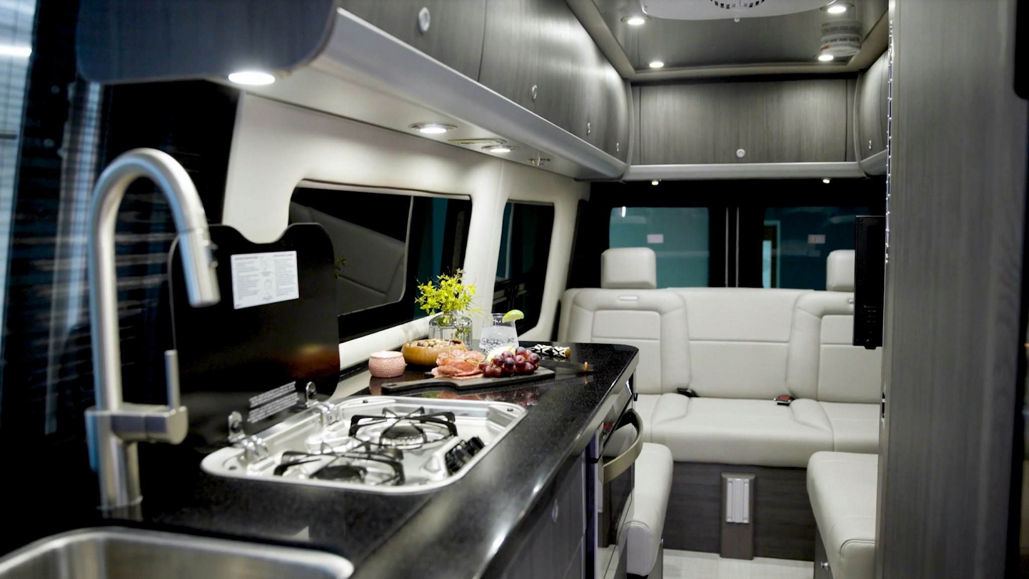Inside an Airstream Touring Coach Class B Motorhome with lux white interior and a platter of grapes sitting on the kitchen counter.