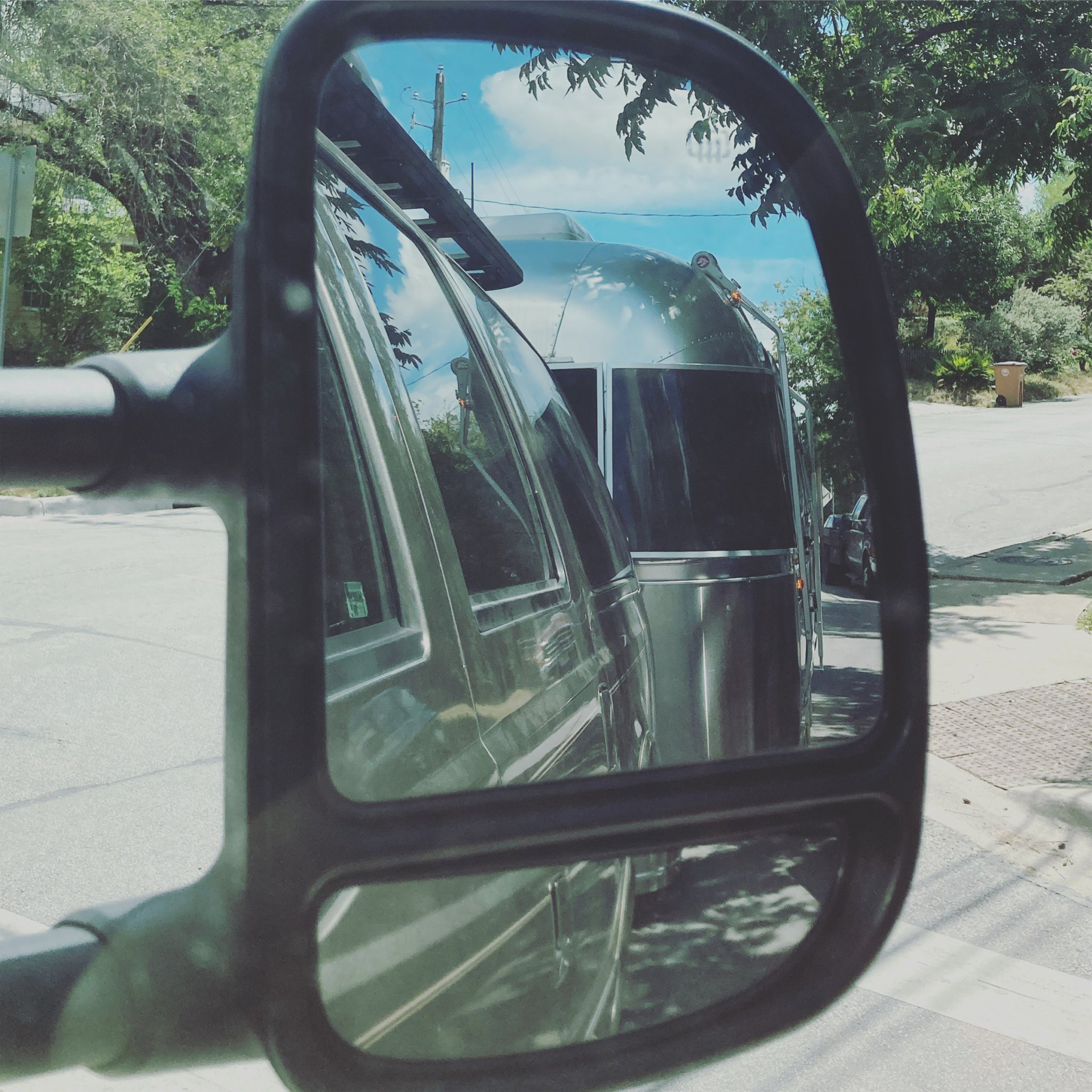 An airstream travel trailer in the mirror of a tow vehicle.