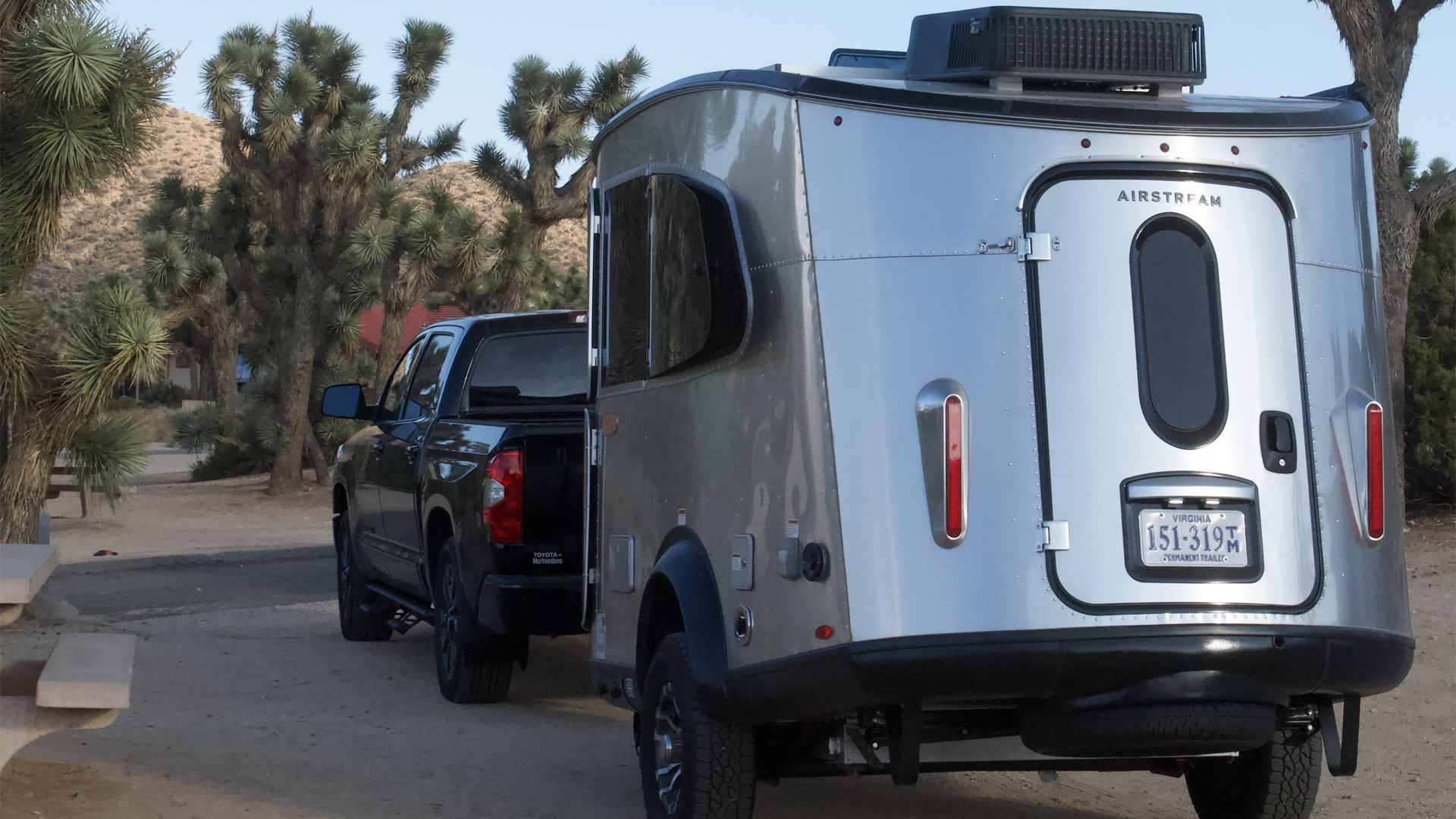 A black truck towing an Airstream Basecamp travel trailer