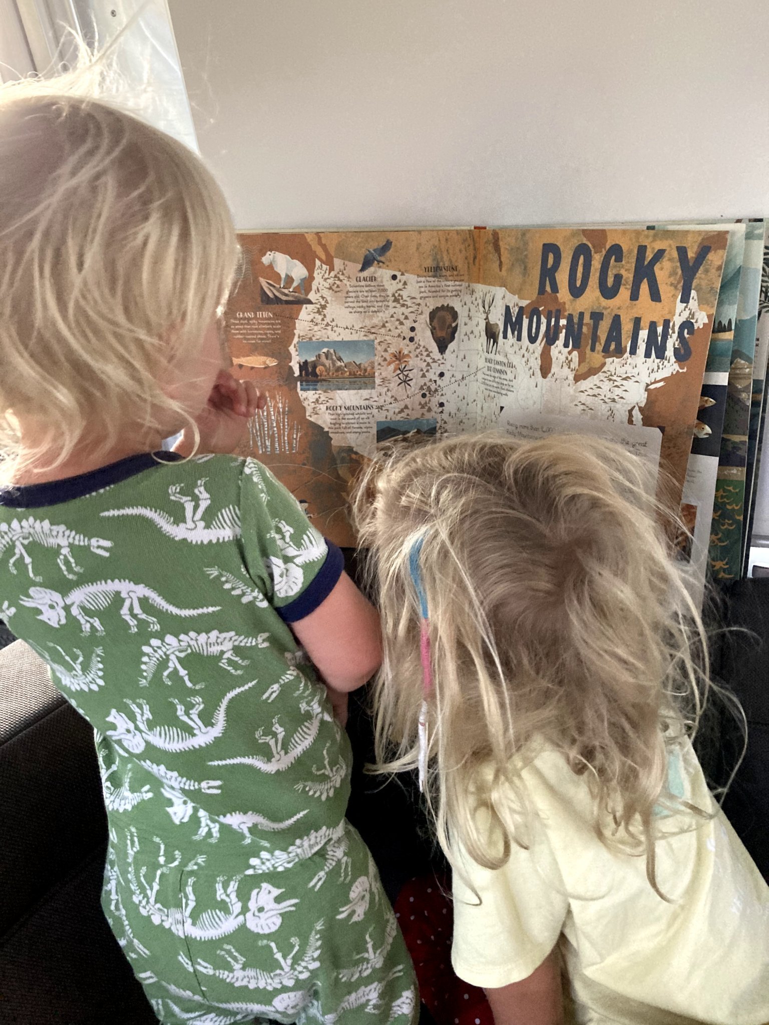 Two kids looking at a map in their Airstream travel trailer while learning on the road.
