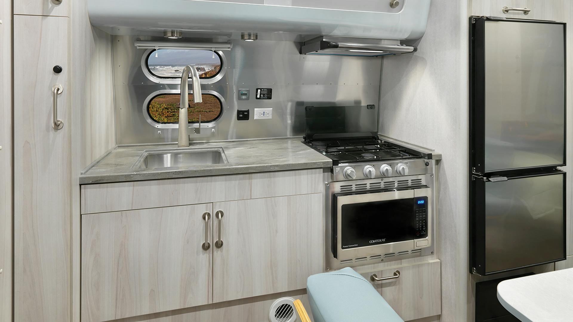The galley of the Airstream 2023 International 23FB travel trailer with a window looking out at scenery in California.