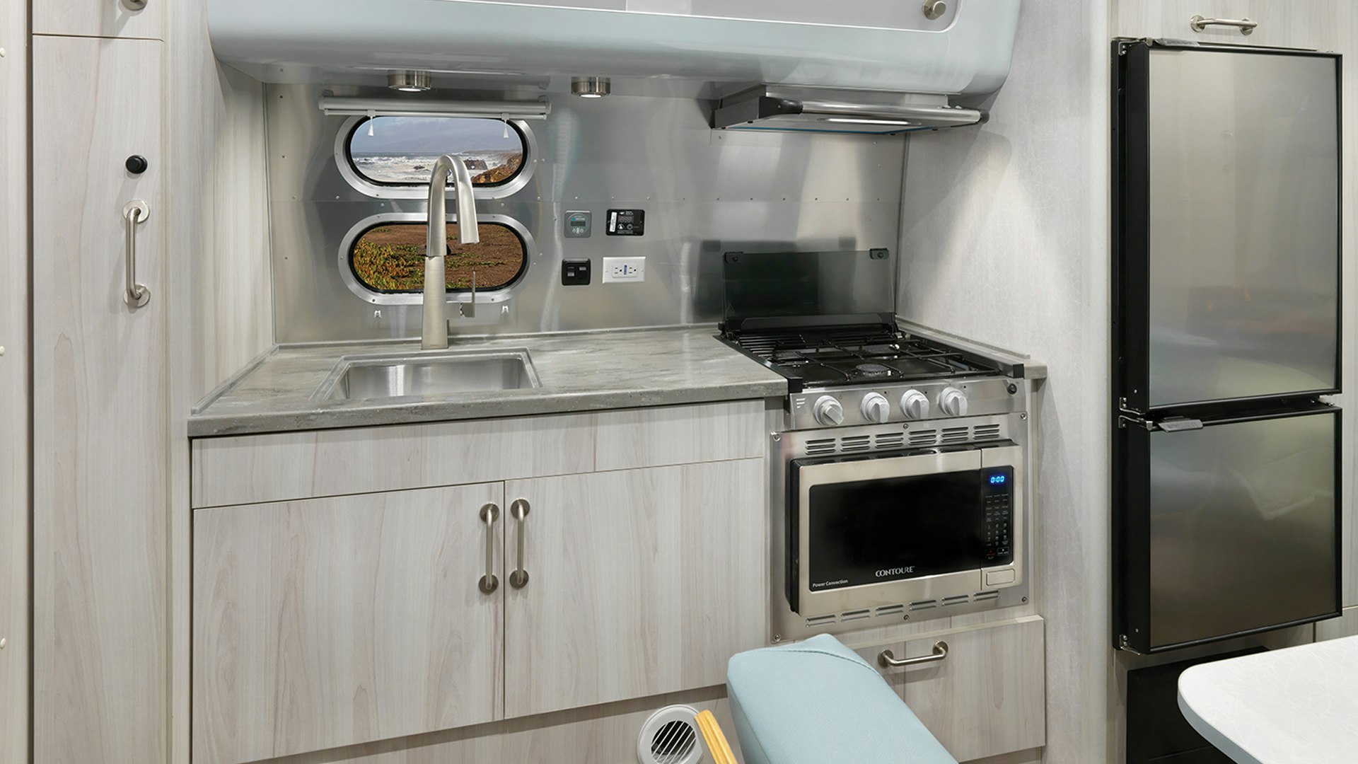 The galley of the Airstream 2023 International 23FB travel trailer with a window looking out at scenery in California.