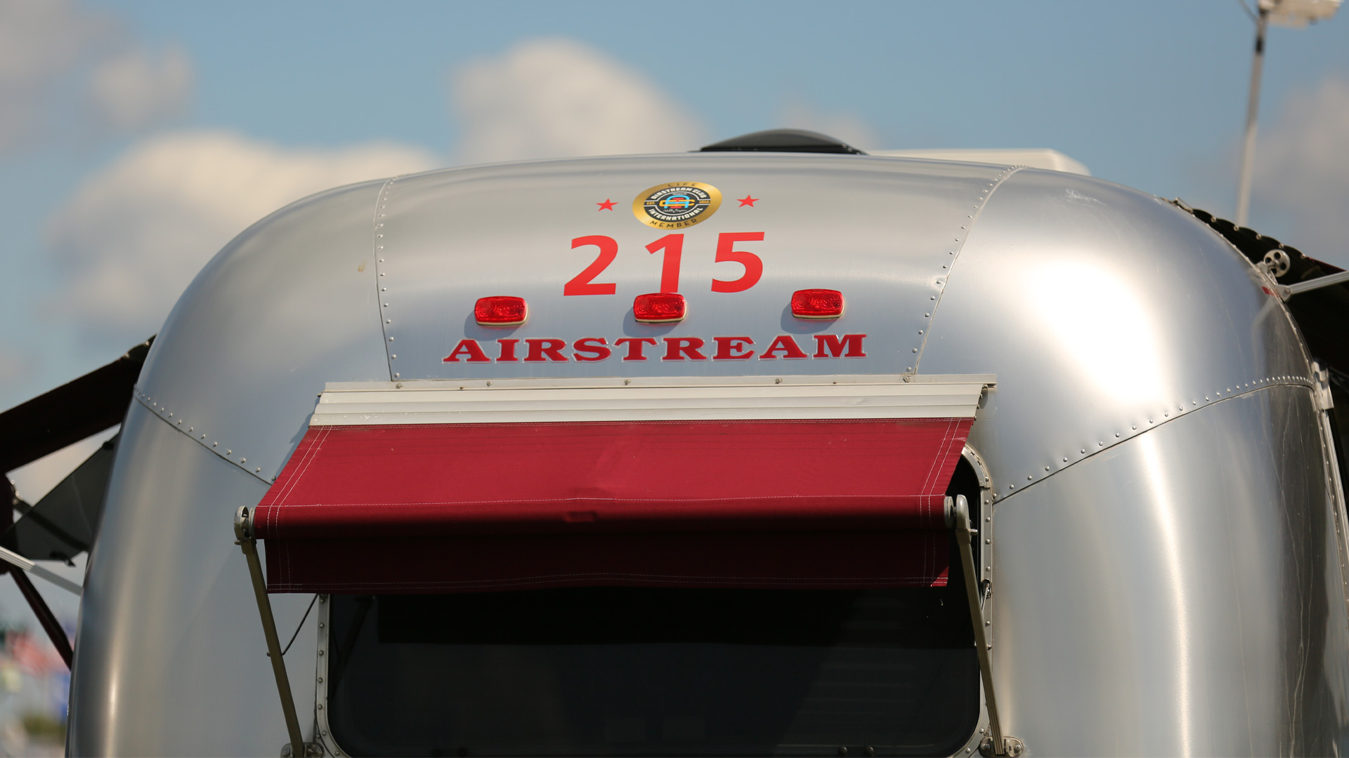 Three red numbers from the Airstream Club on the back of an Airstream Travel Trailer that is at an Airstream rally.