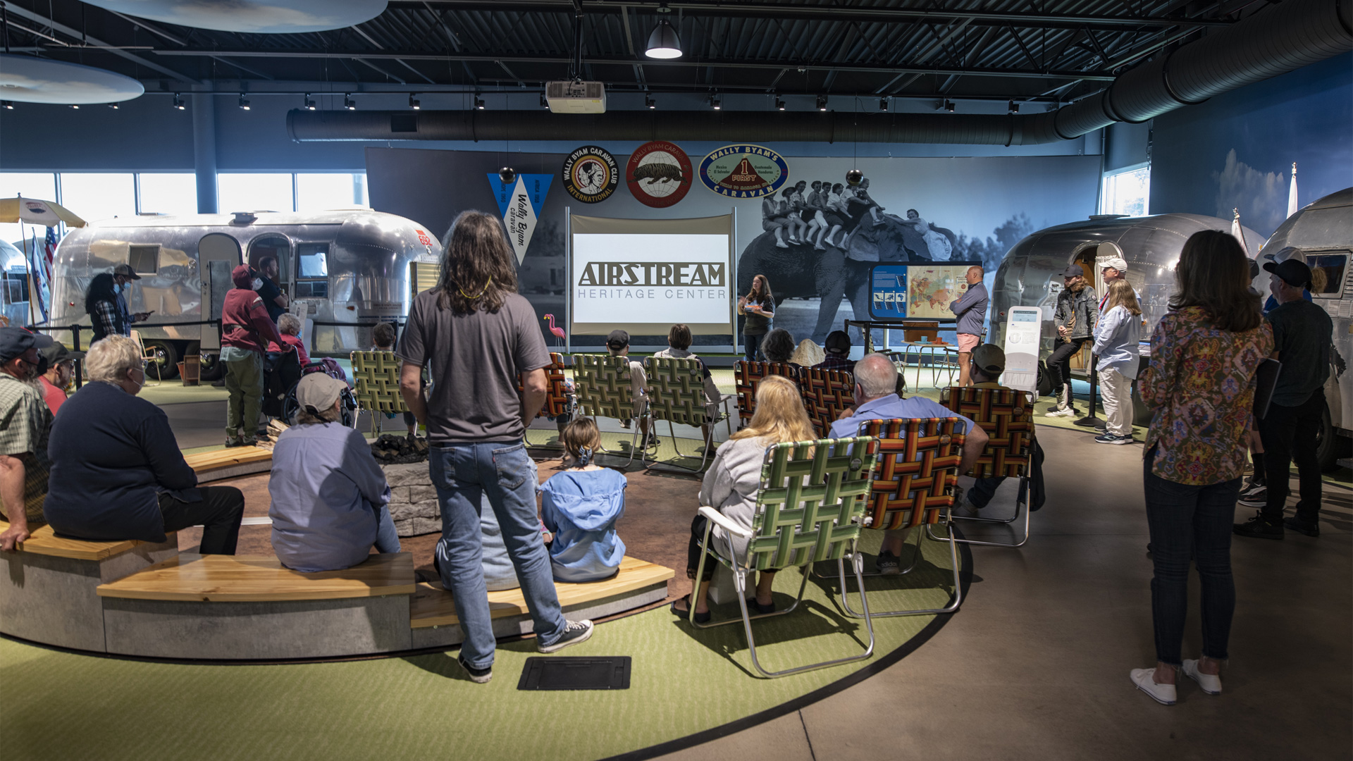 A group of people listening to a presentation in the Airstream Heritage Center during the opening weekend.