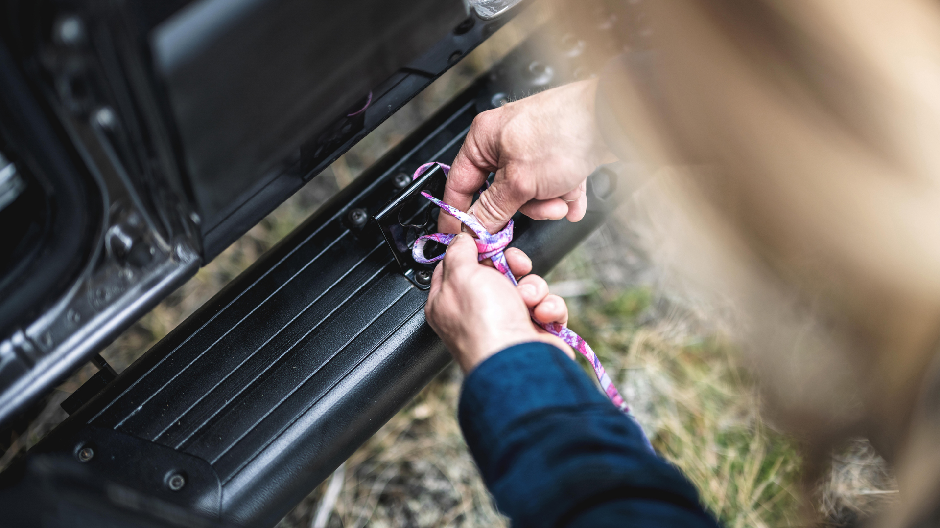 A person tying on a pet leash to the Airstream Rangeline Touring Coach on the exterior.