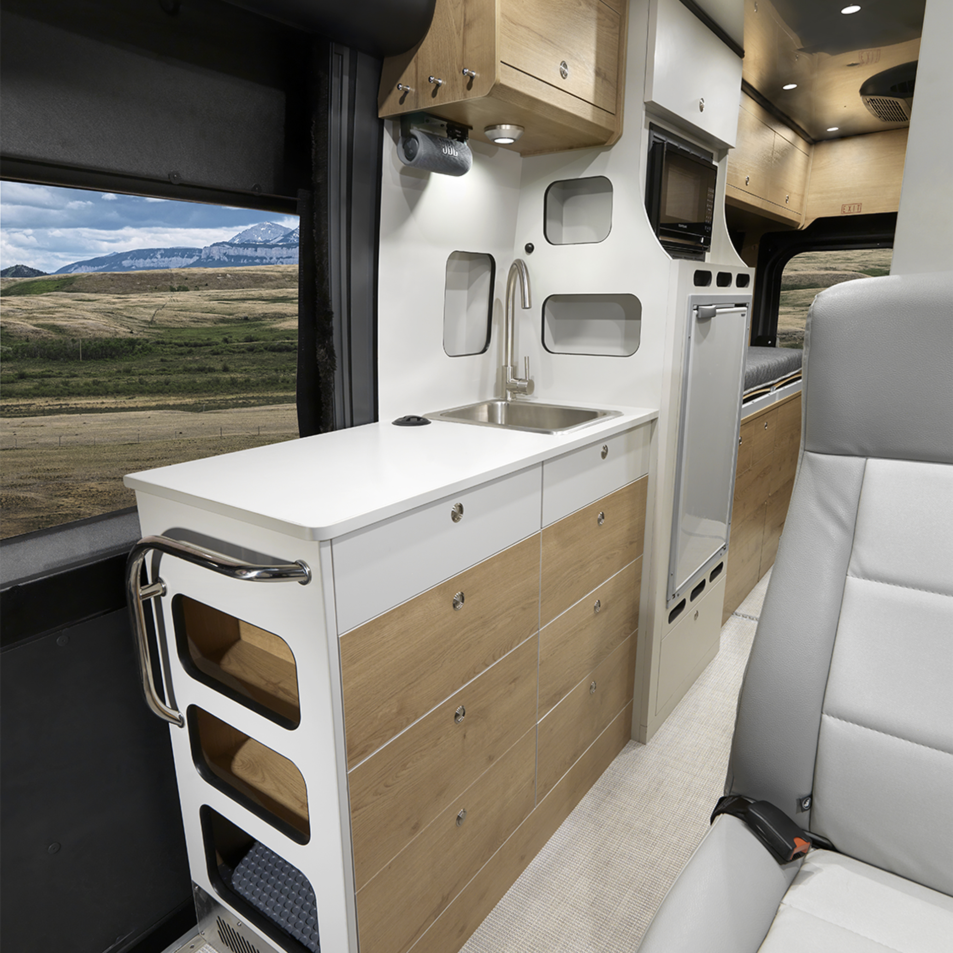 The interior kitchen of the Airstream Rangeline Touring Coach with light colored cabinets and white countertops
