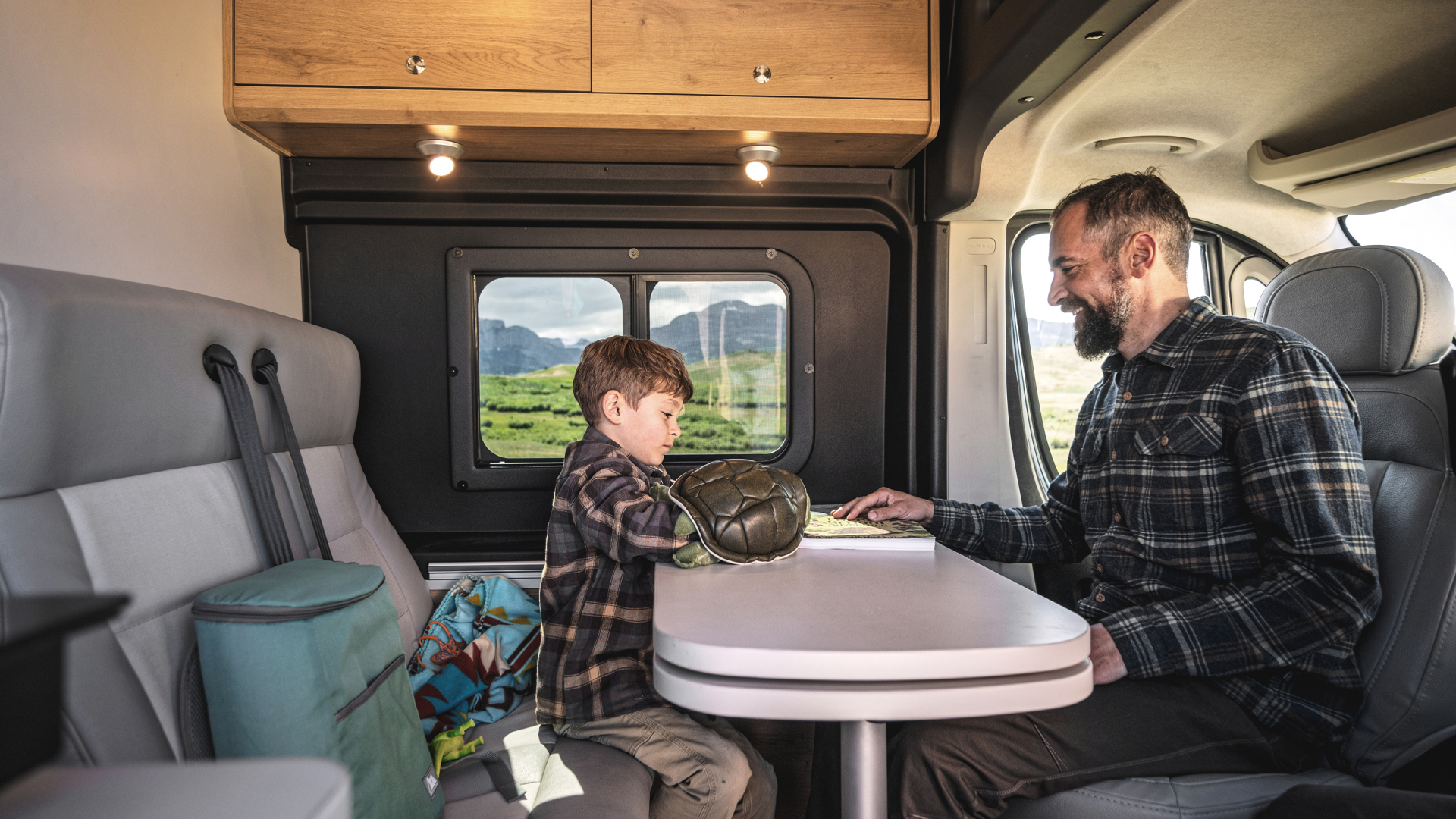 A dad and his son using the tables in the Airstream Rangeline touring coach.