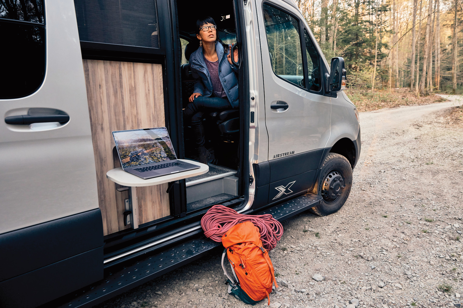 A woman sitting inside the Interstate 24X Class B while she looks outside.